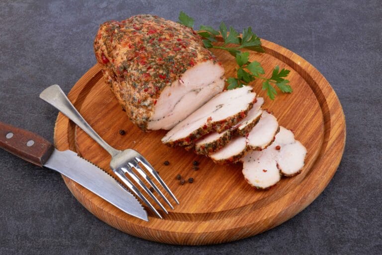 A juicy smoked turkey breast sliced on a wooden cutting board.