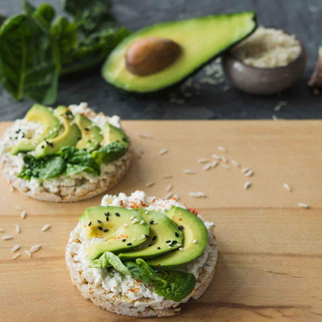 Cottage cheese spread on a rice cake with avocado slices.