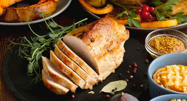 A beautifully smoked turkey breast with crispy skin, resting on a cutting board with herbs and spices around it.