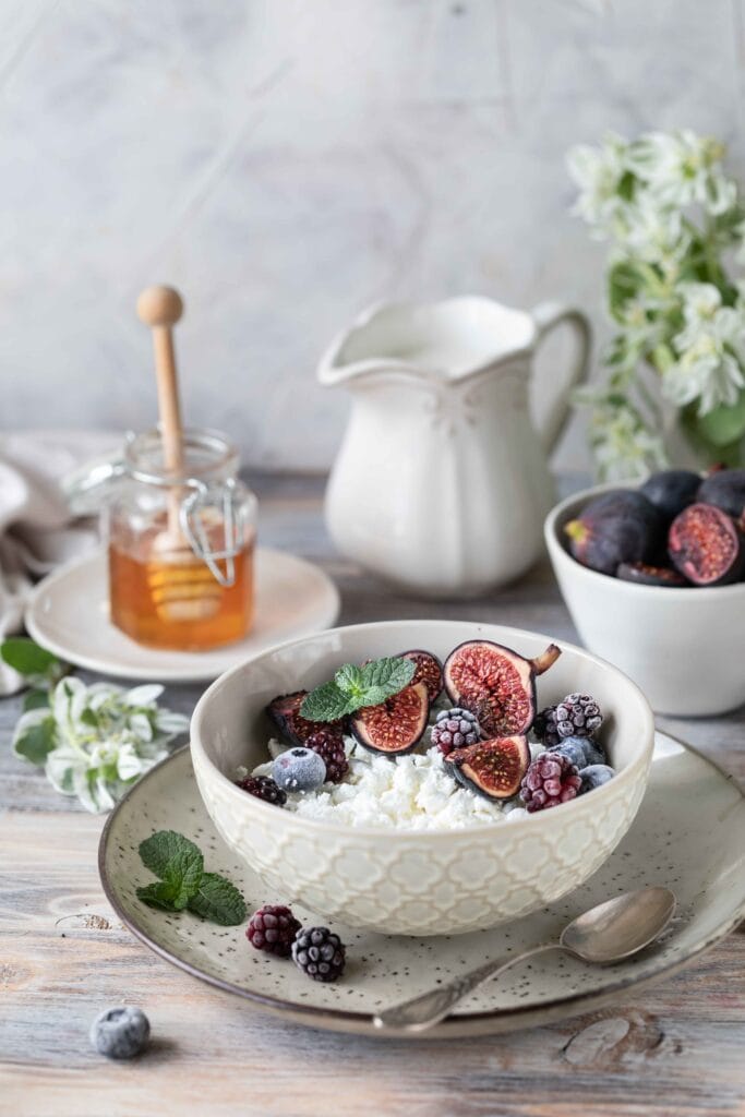 Cottage cheese topped with mixed fresh fruits like berries, bananas, and a drizzle of honey.