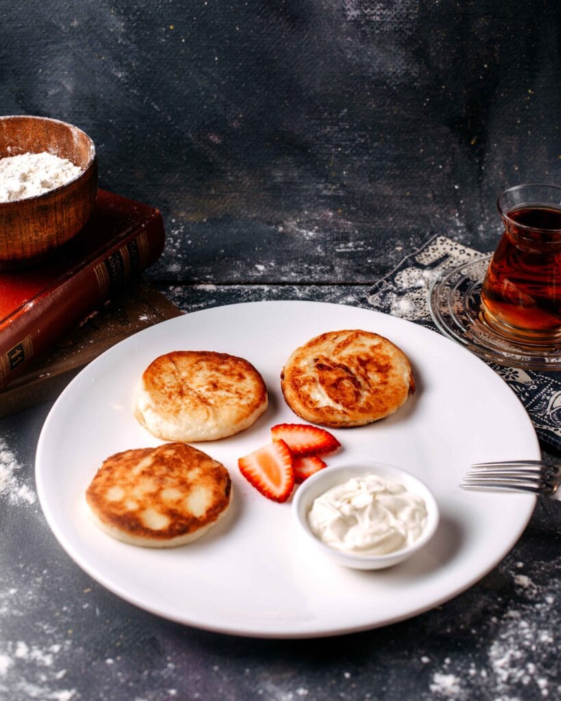 Cottage cheese pancakes served with syrup and fresh berries.