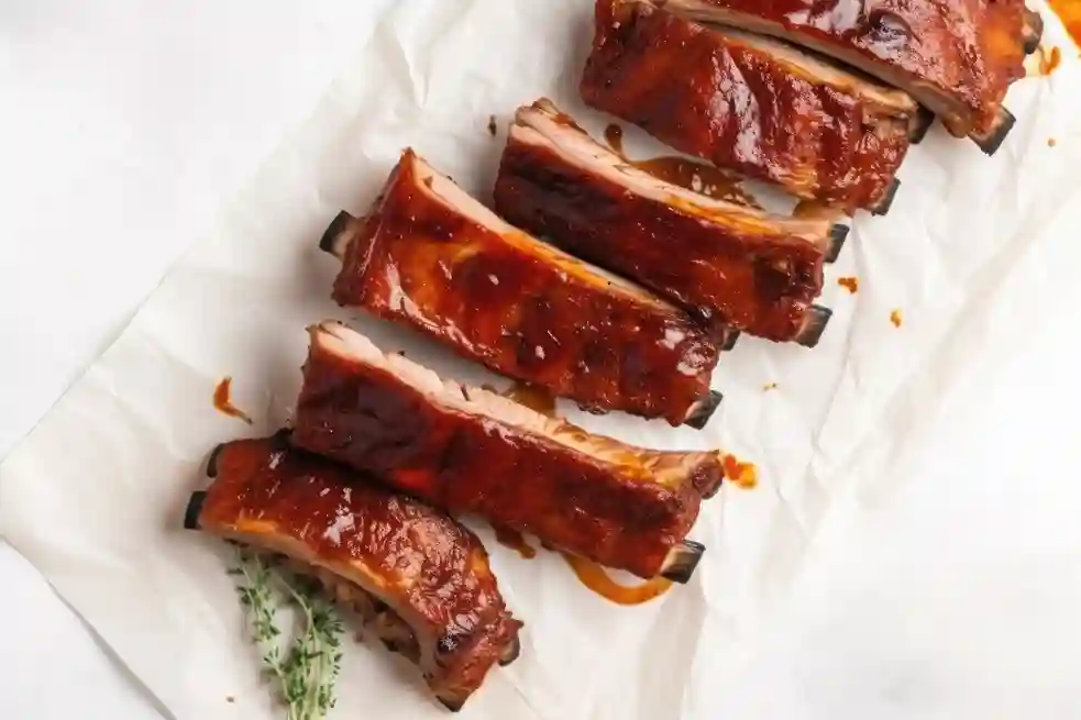 Back ribs in a baking dish with barbecue sauce.