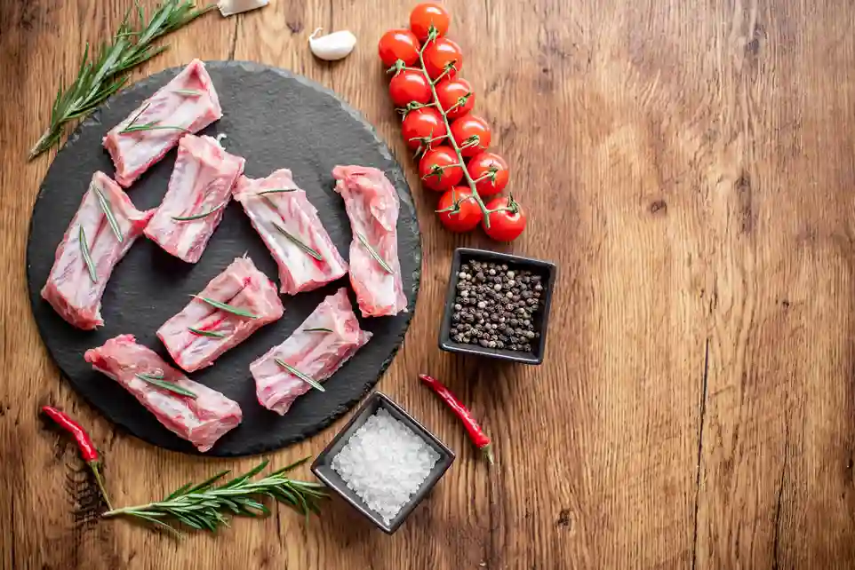 Beef ribs and beef back ribs displayed side by side on a wooden cutting board.