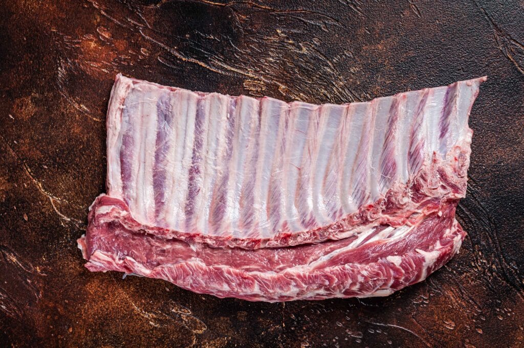 Removing the membrane from beef back ribs using a knife and paper towel.