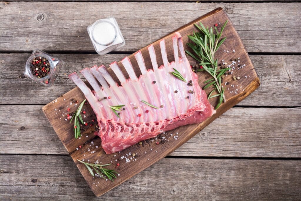 A raw cut of beef back ribs on a wooden board, showing the bone structure and marbling.