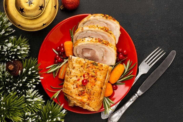 Smoked turkey breast on a wooden cutting board with herbs and side dishes