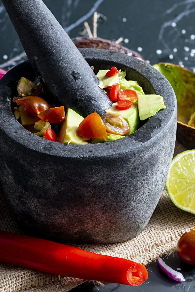 Traditional molcajete with ingredients like avocados, tomatoes, and garlic.