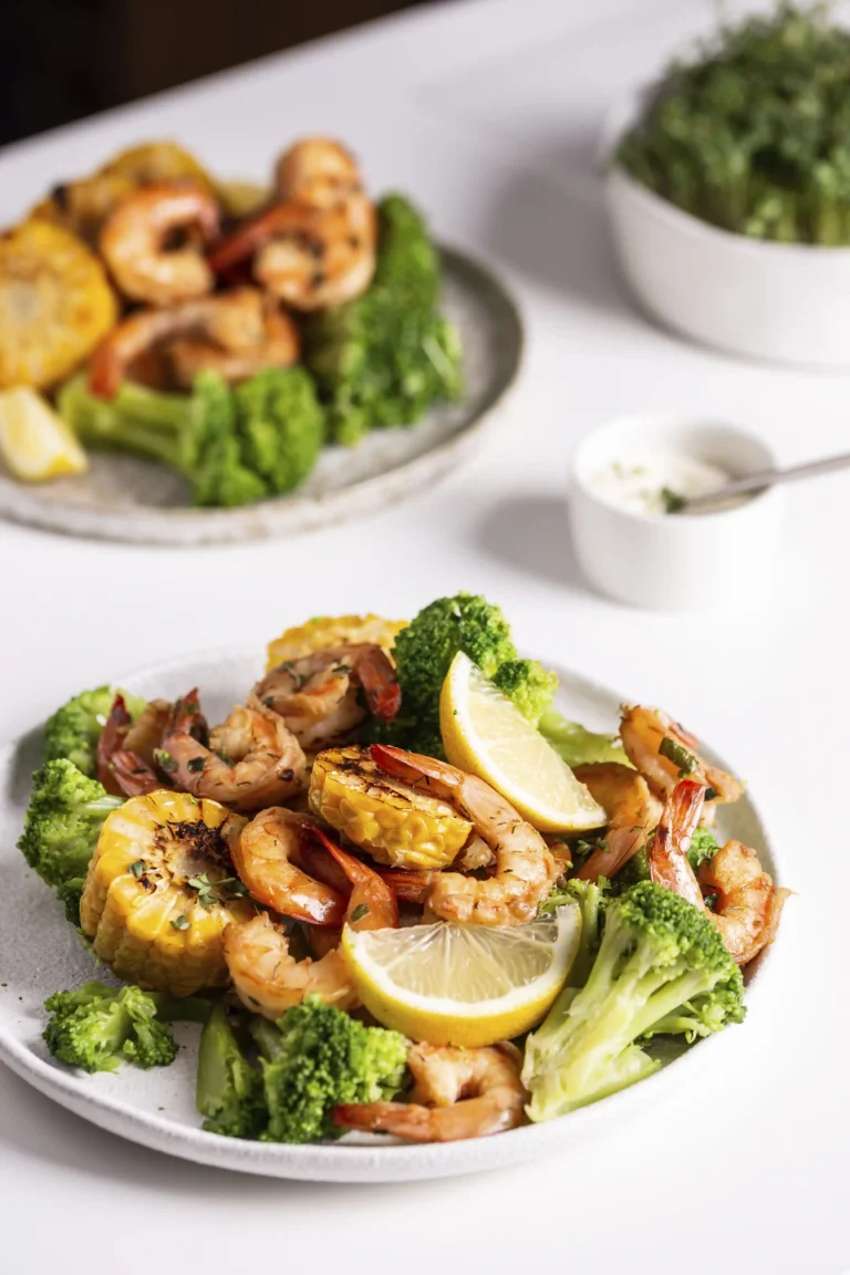 A plate of BBQ shrimp surrounded by a variety of side dishes like coleslaw, cornbread, and grilled vegetables.