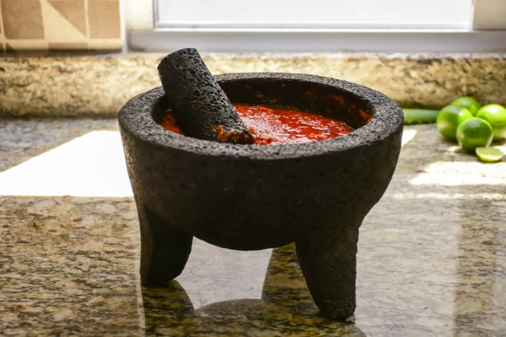 Fresh salsa being ground in a molcajete.