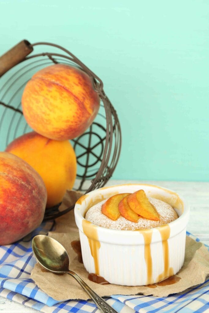 A freshly baked peach cobbler with biscuit topping in a white dish.
